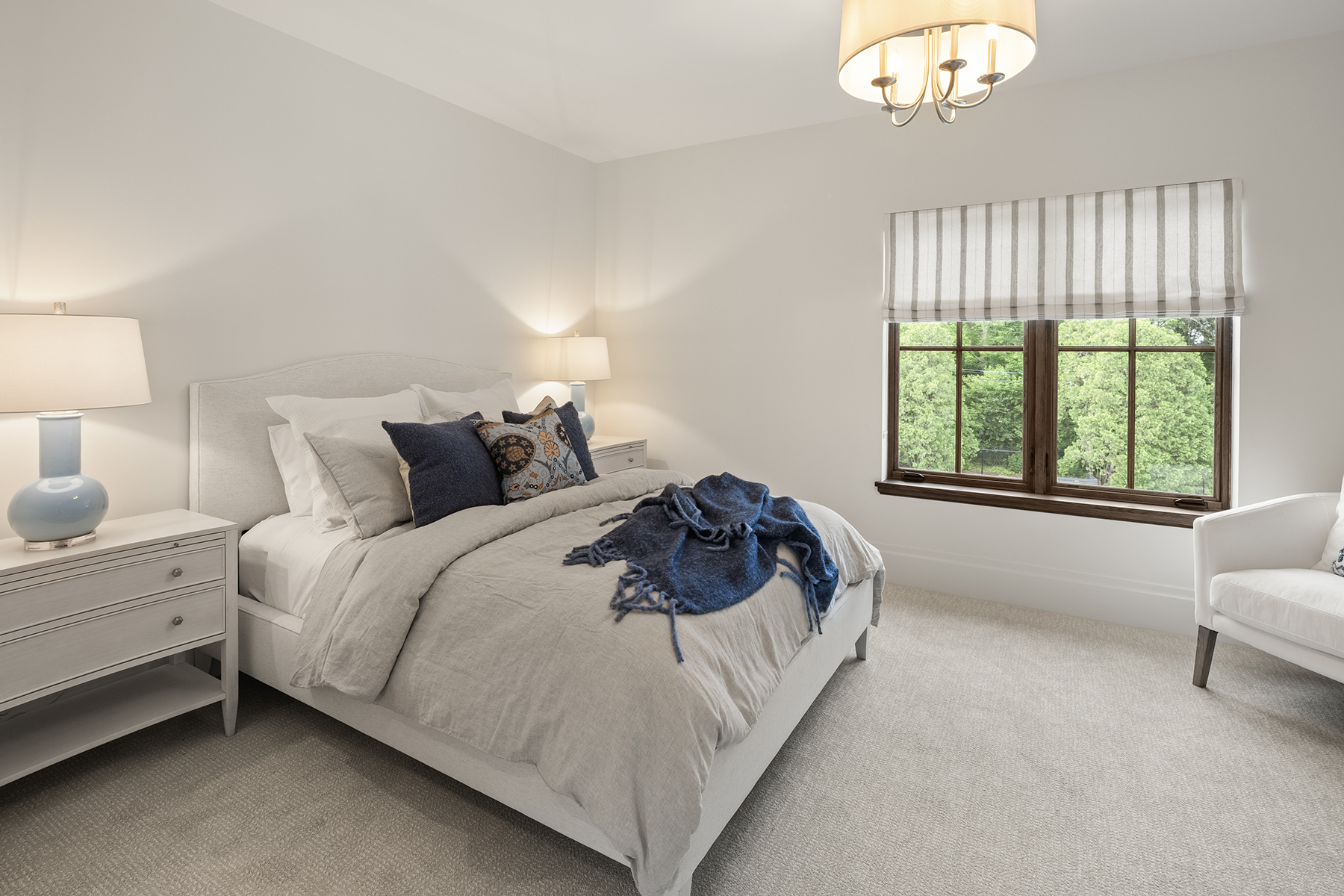 Highcroft guest bedroom in soft neutrals with striped roman shade