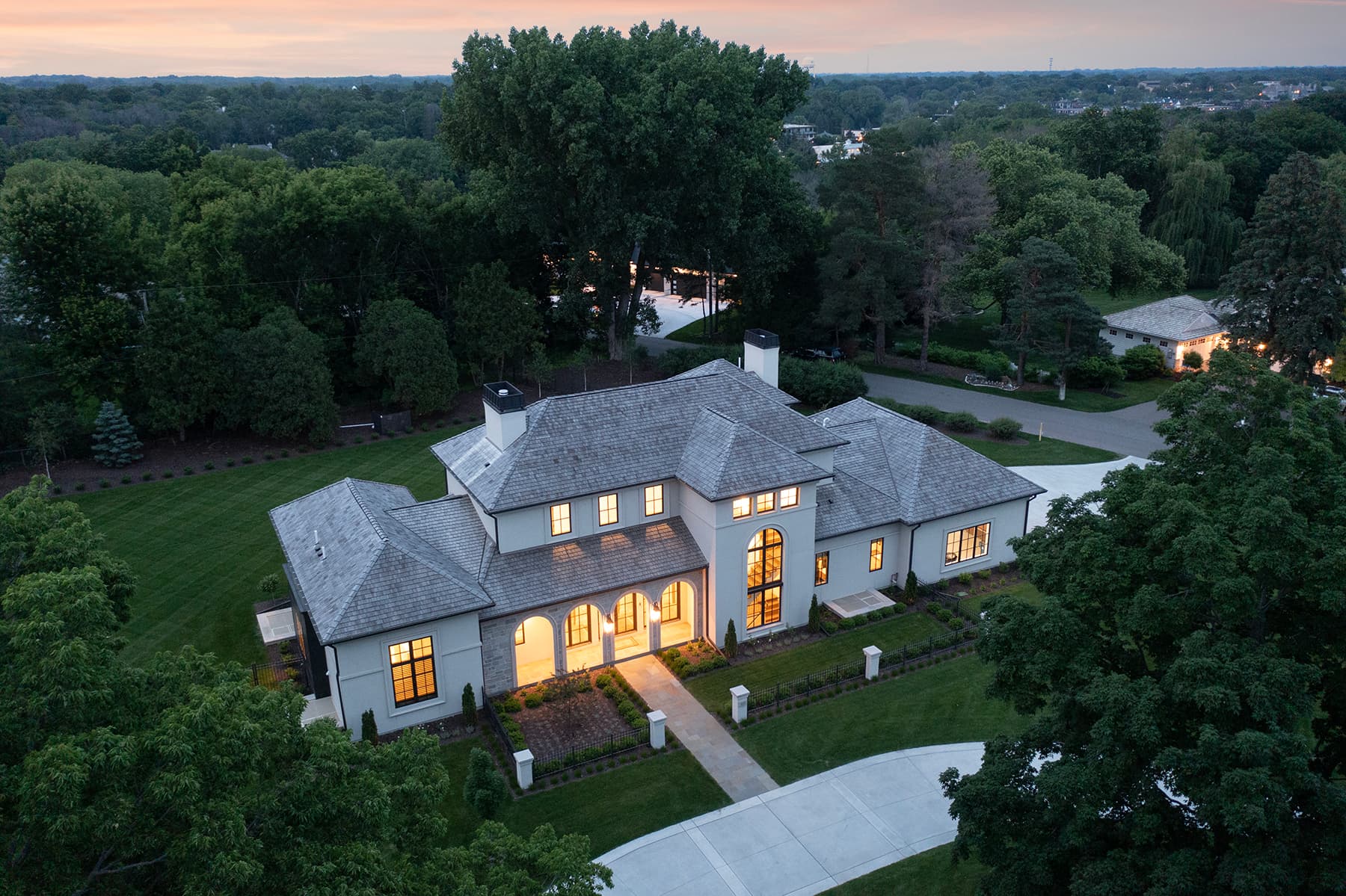 Aerial view of Highcroft glowing at dusk among mature oaks