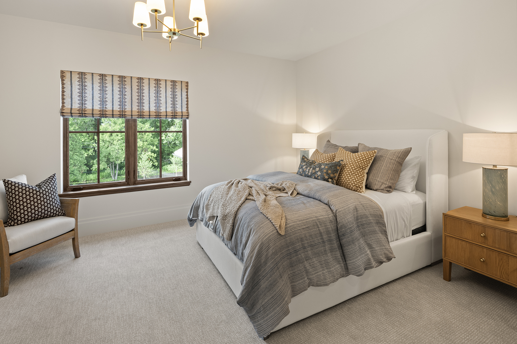 Highcroft guest bedroom with patterned roman shade and warm layered textiles