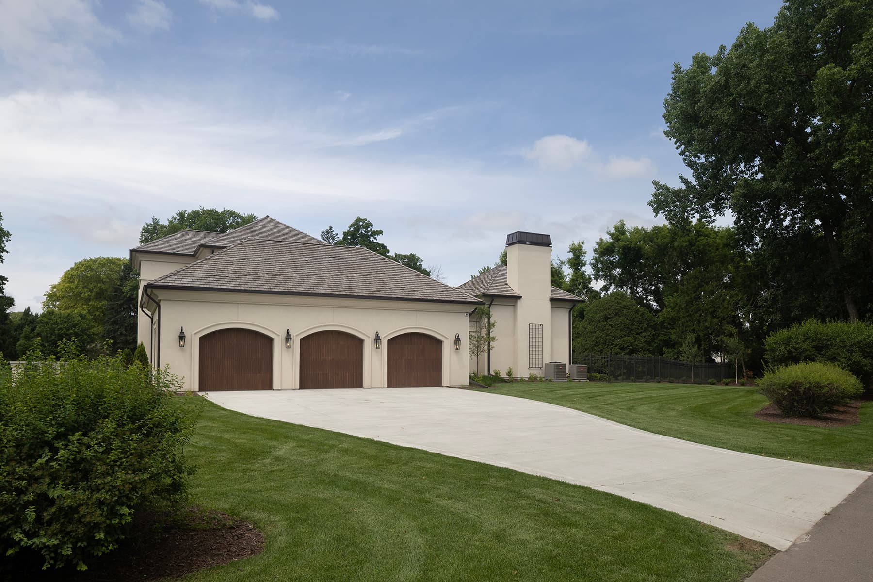 Highcroft garage wing with arched wood doors and cedar shake roof