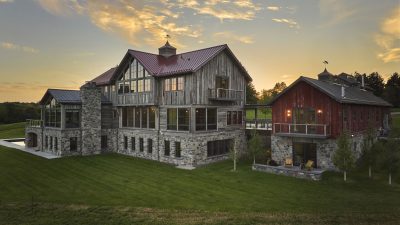 Timber Retreat exterior with stone and timber gables at sunset