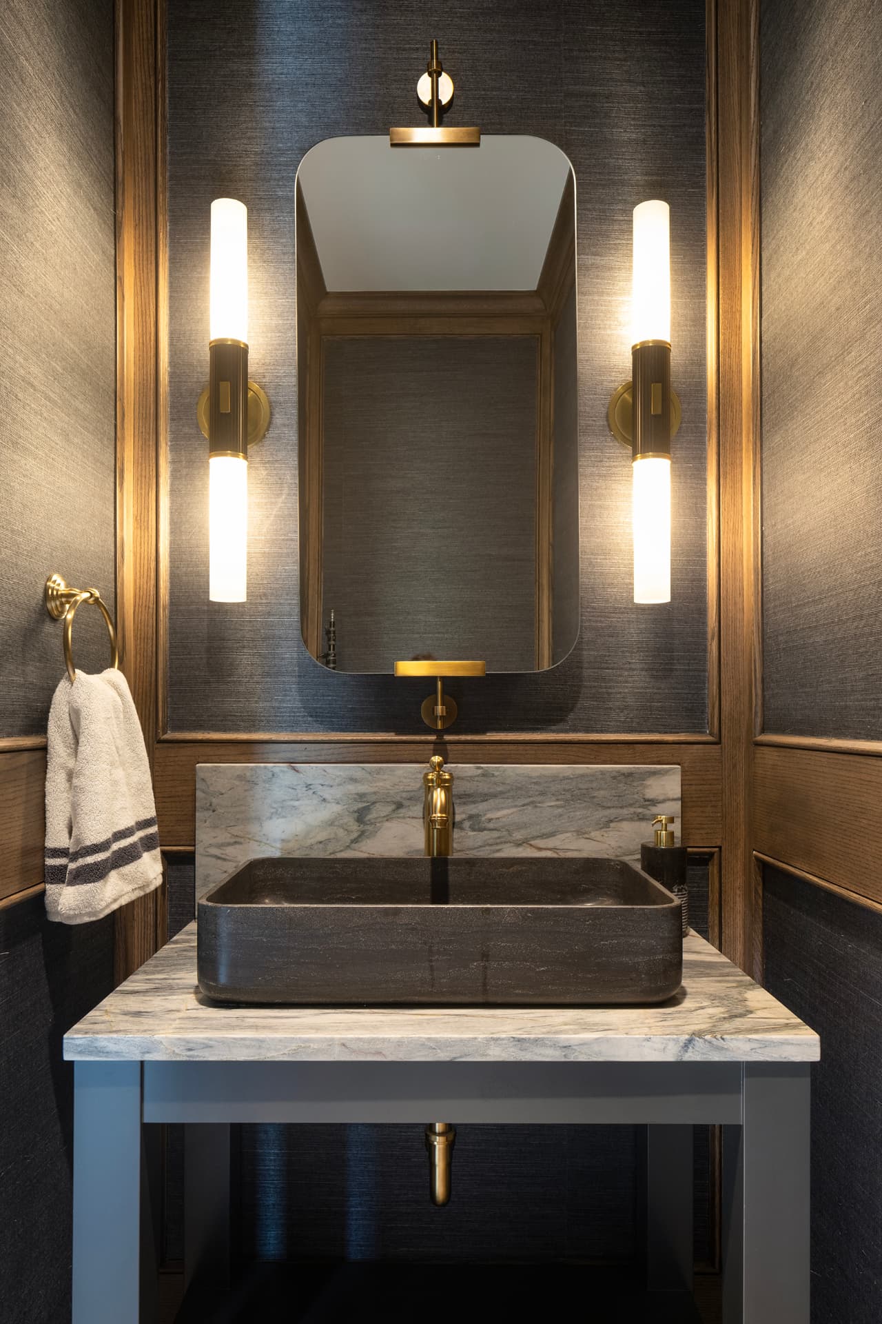 Highcroft powder room with stone vessel sink and brass sconces