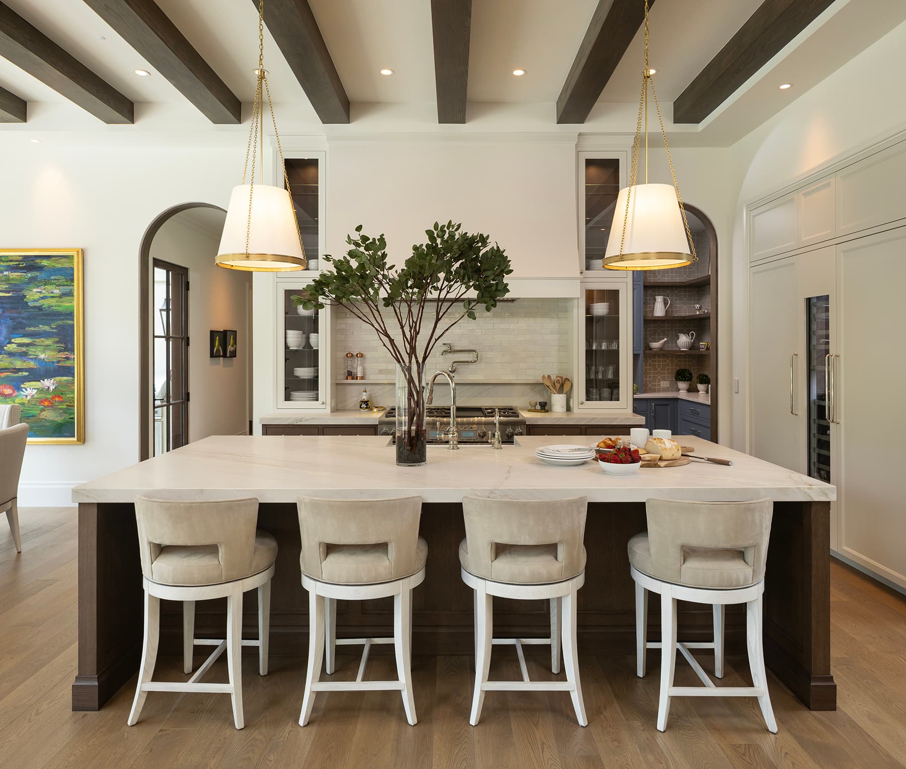 Highcroft kitchen island with upholstered bar stools and brass pendant lights