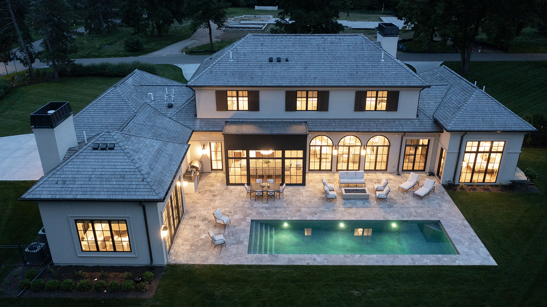 Elevated view of Highcroft's rear elevation and lit pool at nightfall
