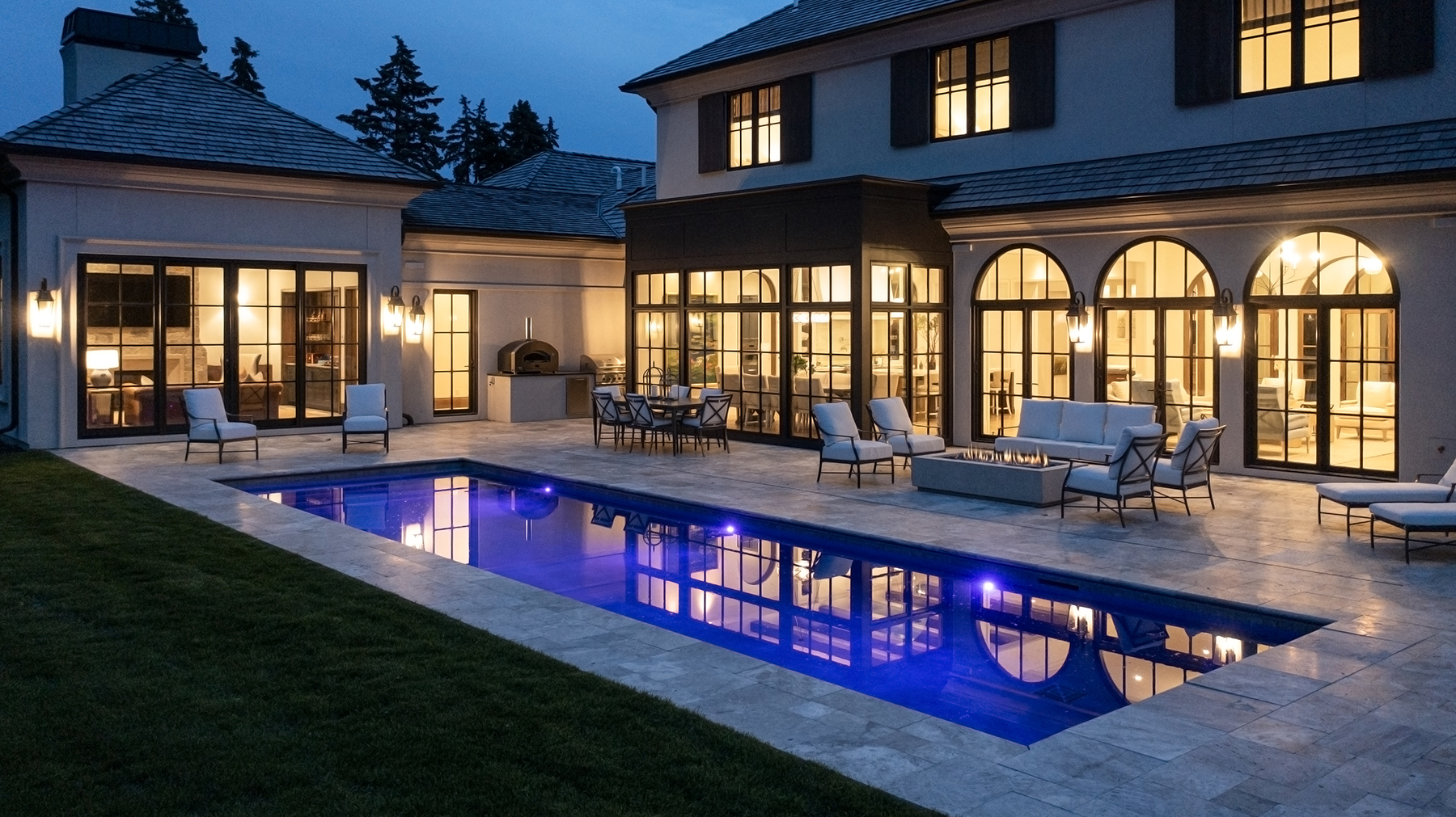 Highcroft pool terrace at blue hour with fire table and arched loggia