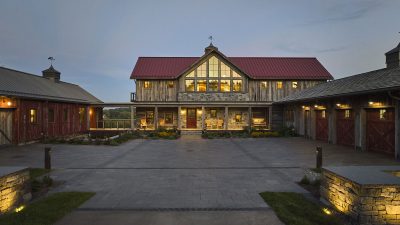 Timber Retreat courtyard approach between stone and timber buildings at dusk