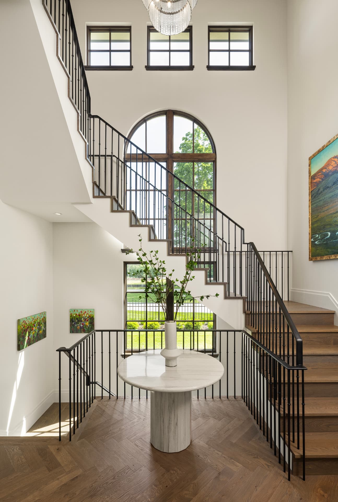 Highcroft stair hall with arched window, iron rail and herringbone oak