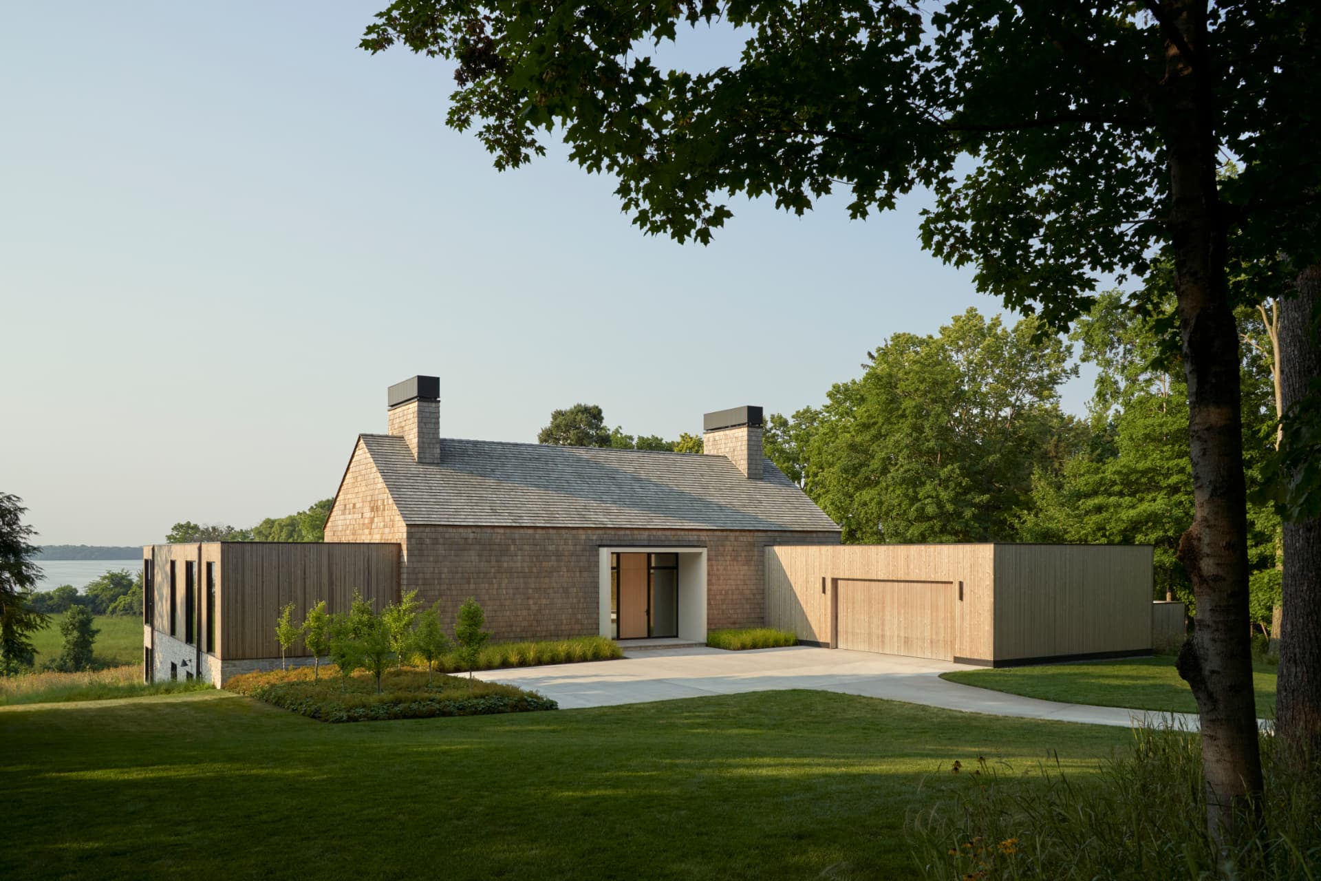 Hill House exterior framed by mature trees with Lake Minnetonka beyond