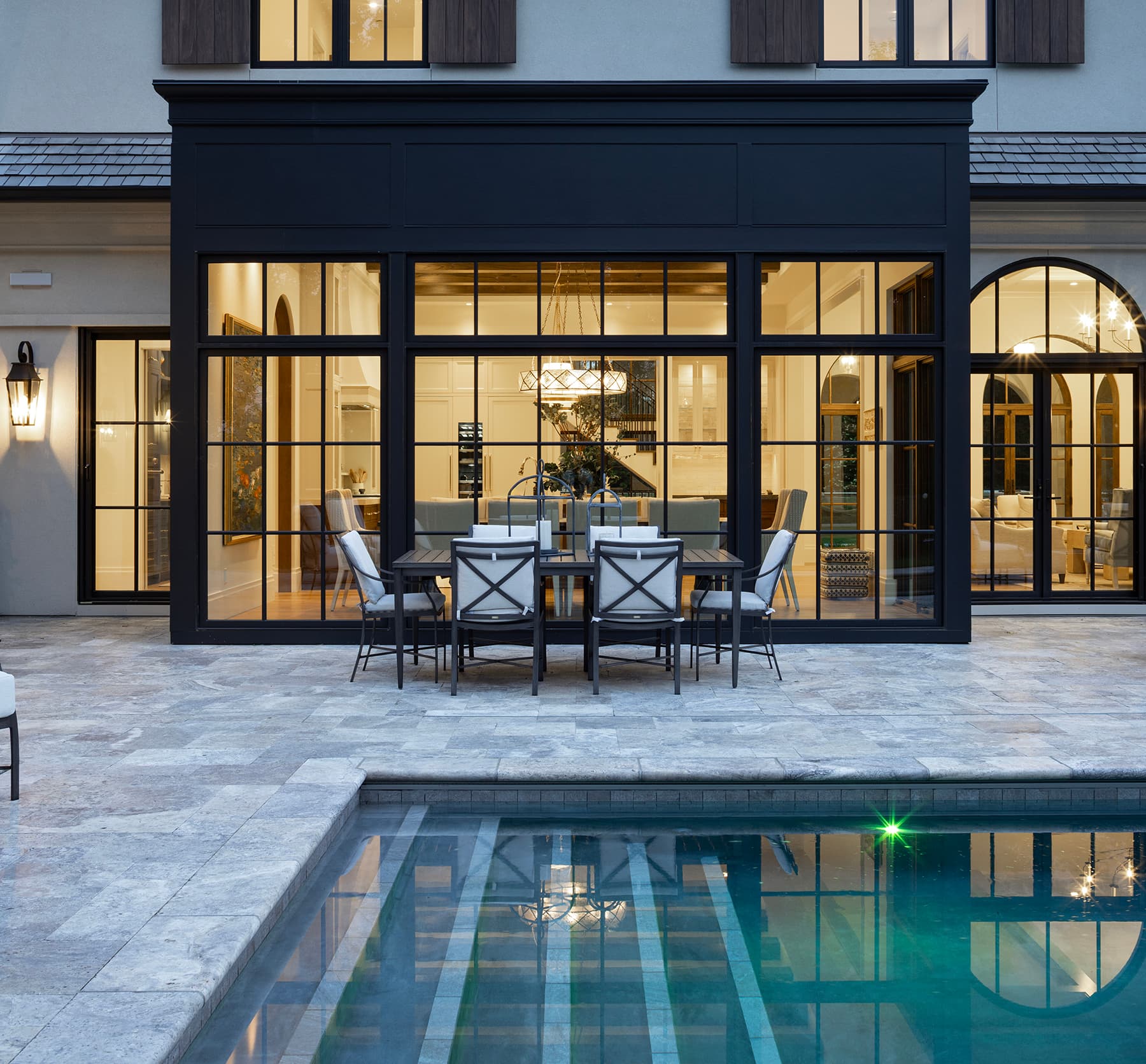 Highcroft conservatory glowing over the pool terrace at blue hour