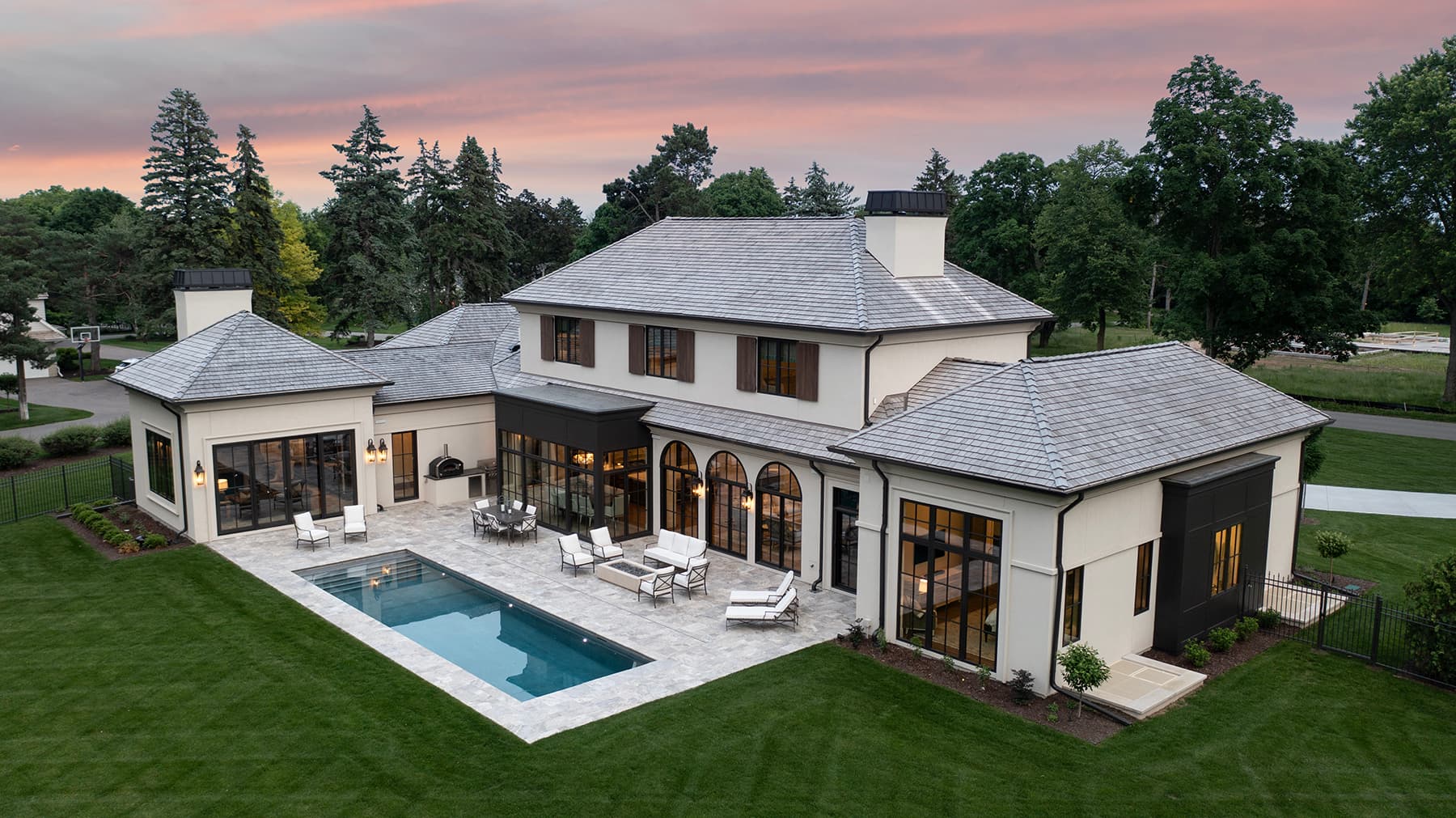 Aerial of Highcroft's rear elevation, pool and terrace at sunset