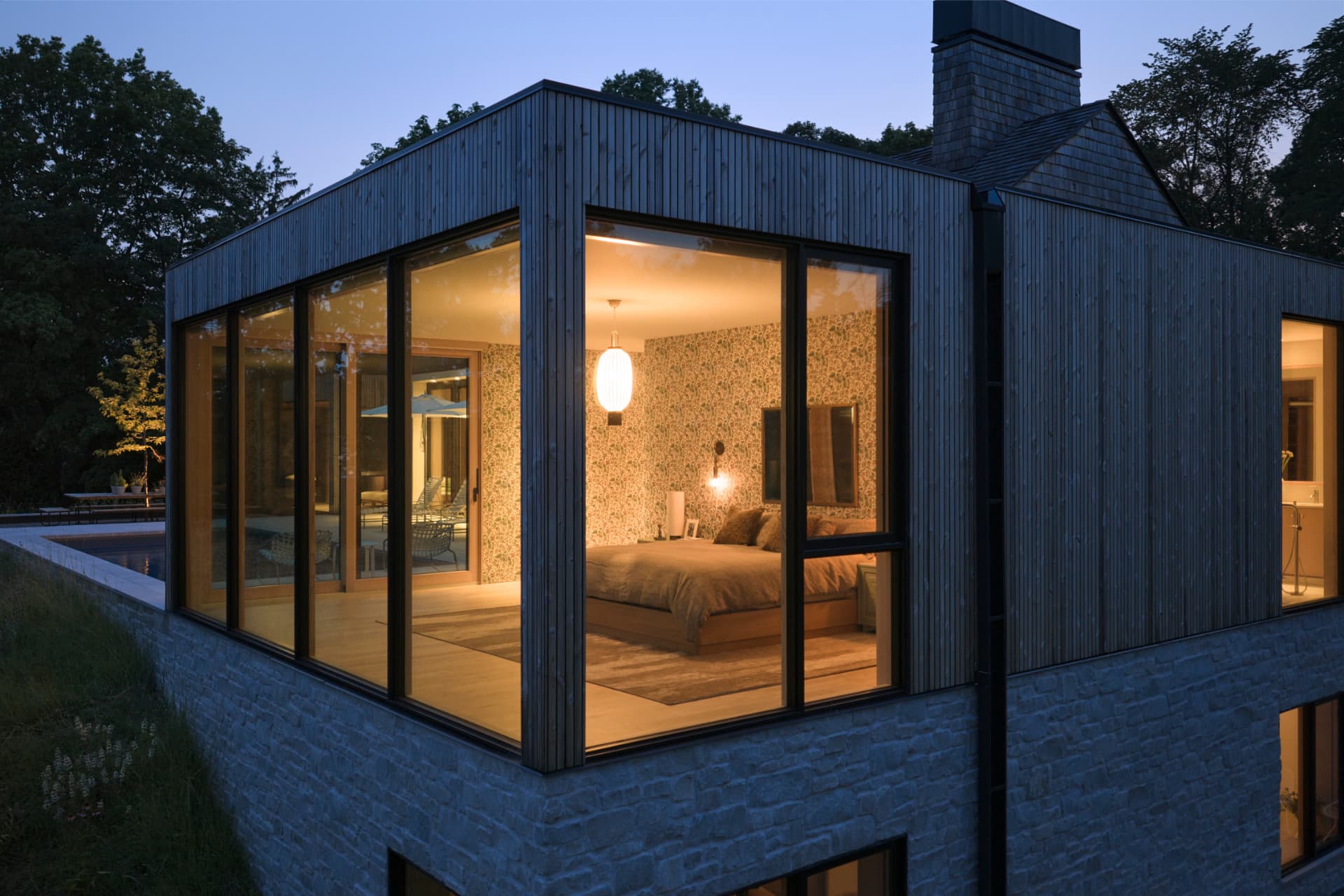 Hill House glass-walled bedroom glowing at twilight