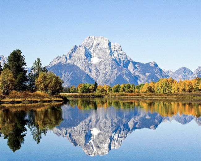 Scenic mountain reflecting in a crystal-clear lake surrounded by lush trees