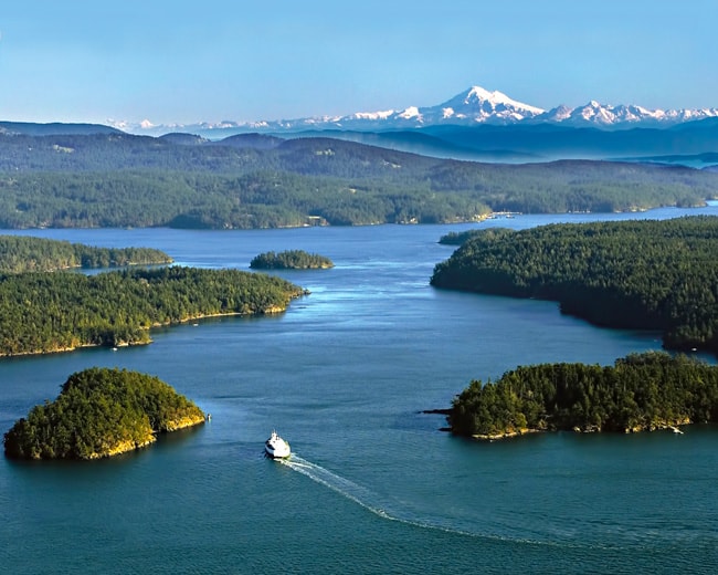 aerial photo san juan islands with boat in bay and mountains in background